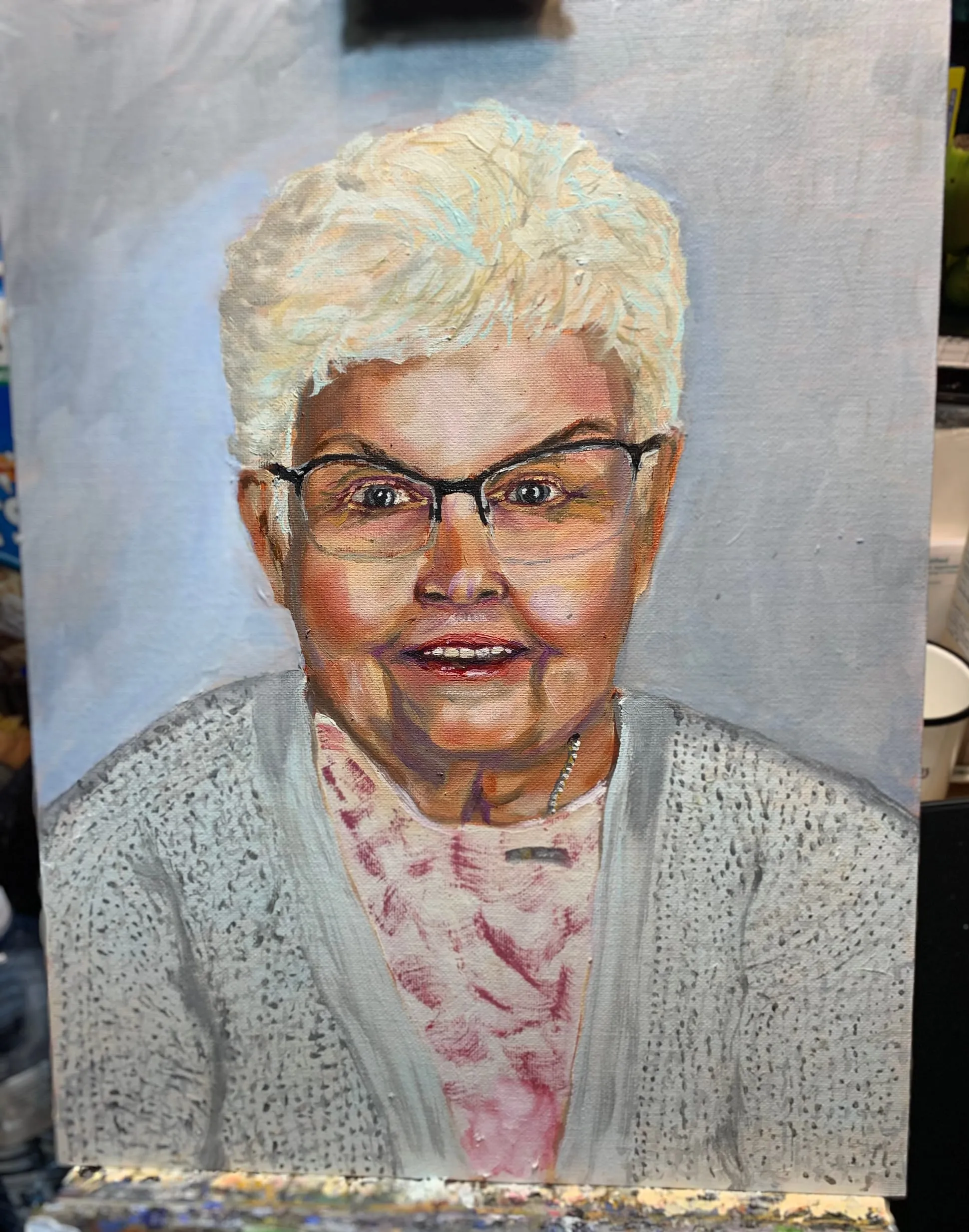 Portrait painting of a woman with short white hair, glasses and a pale cardigan.