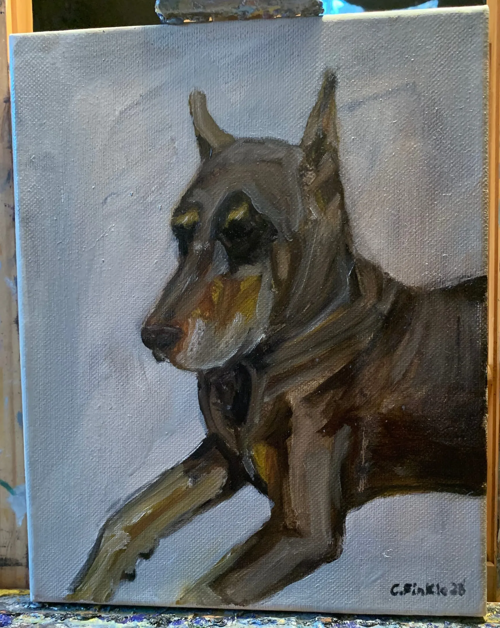 Painting of a dark-coated dog reclining against a blue-grey background.