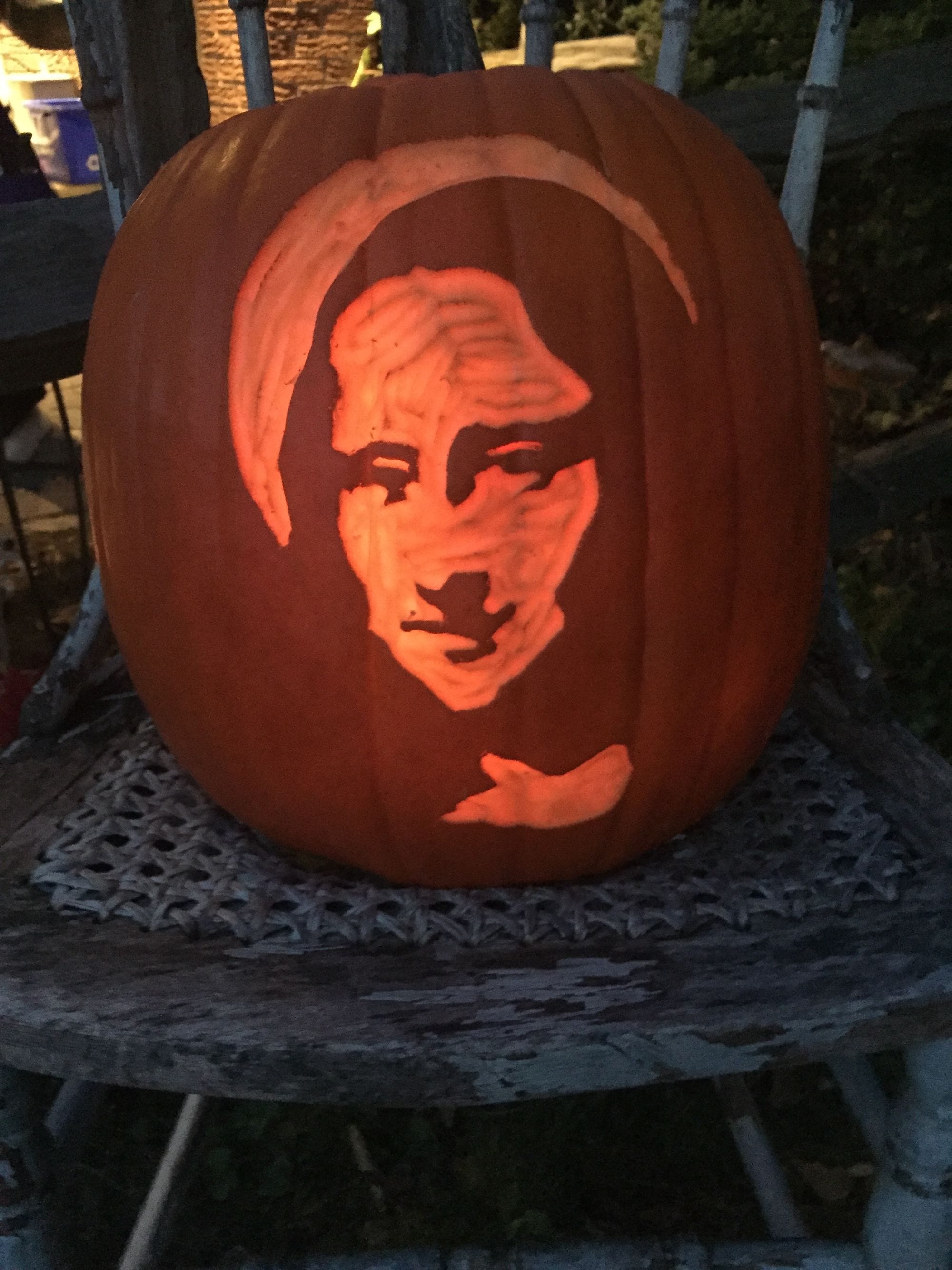 Pumpkin carved with a closely cropped or bald head and deeply shadowed features.