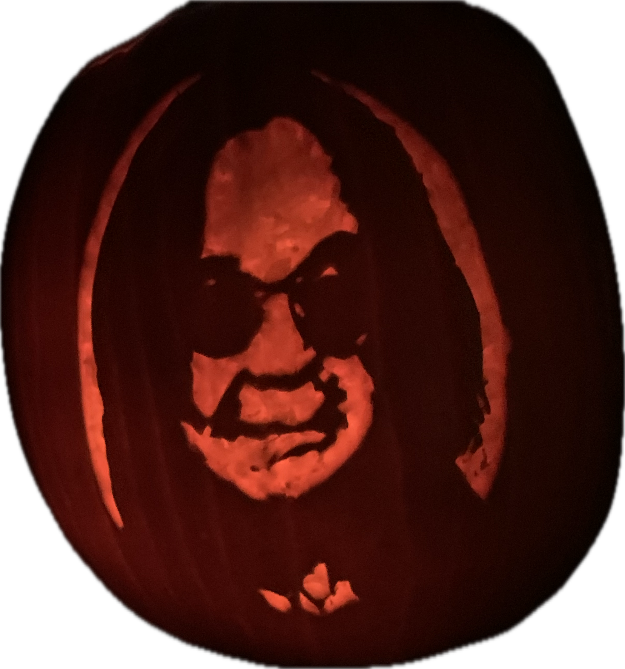 Illuminated pumpkin carving depicting a long-haired face wearing dark sunglasses.