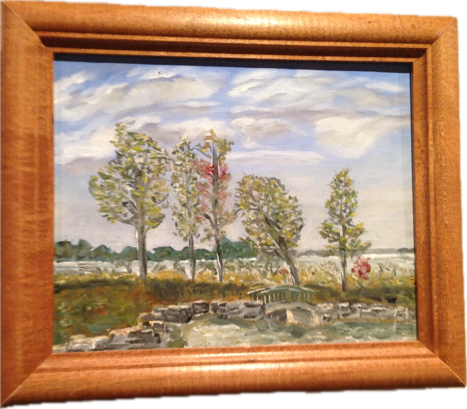 Framed painting of a waterside trail with trees, rocks and a small footbridge.