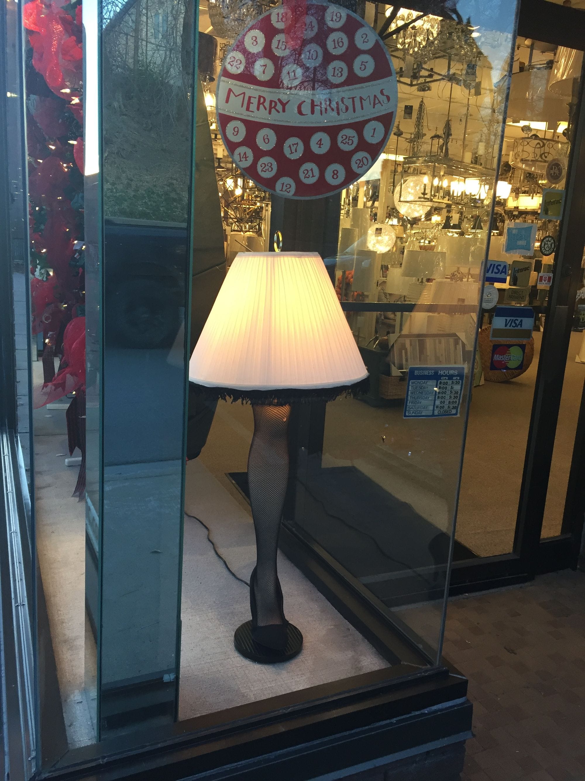 Illuminated table lamp with a leg-shaped base, photographed in a shop window.