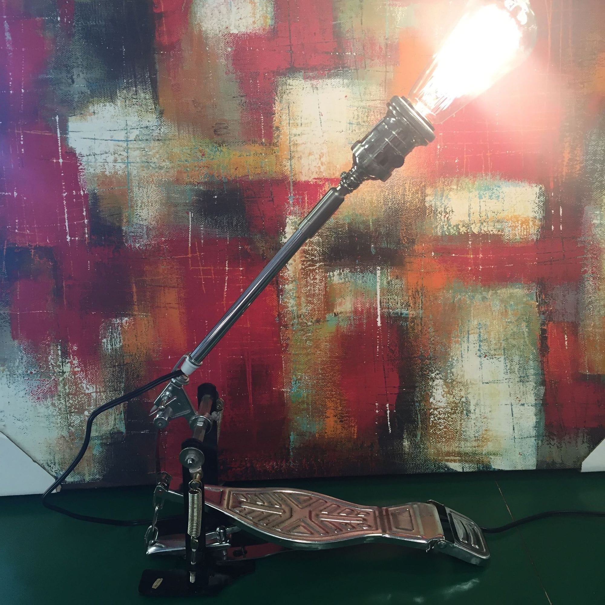 Adjustable exposed-bulb lamp built on a drum pedal.