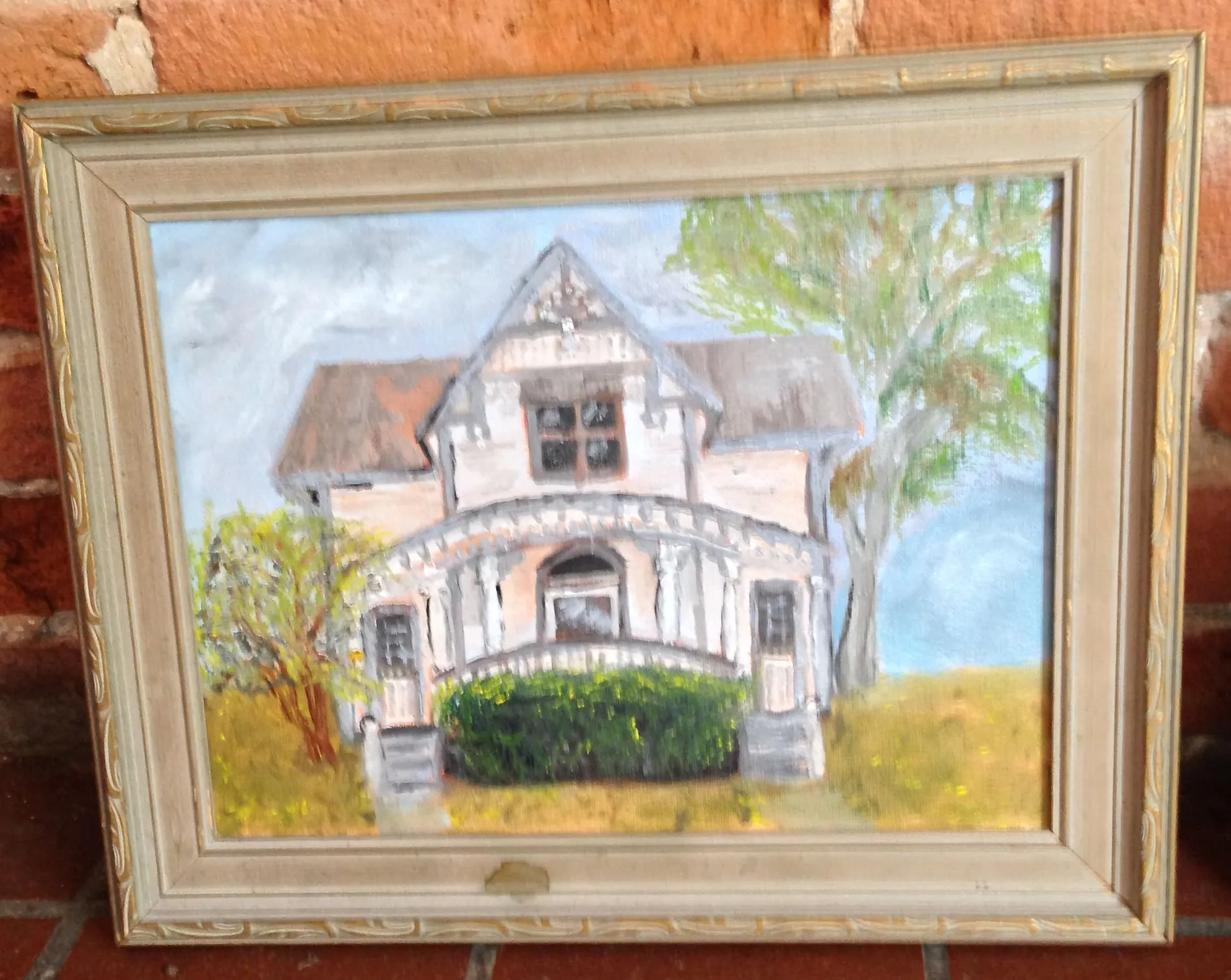 Framed painting of an ornate house with a gabled roof and porch.
