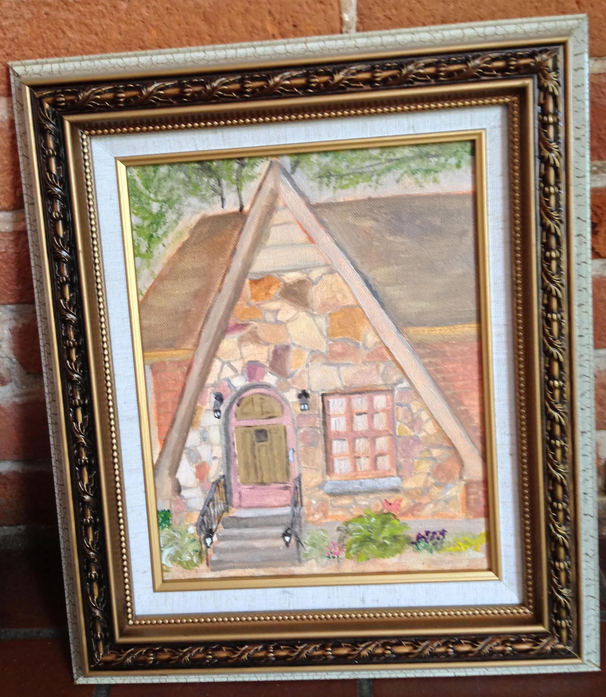 Framed painting of a steeply gabled stone entrance with a pink doorway.