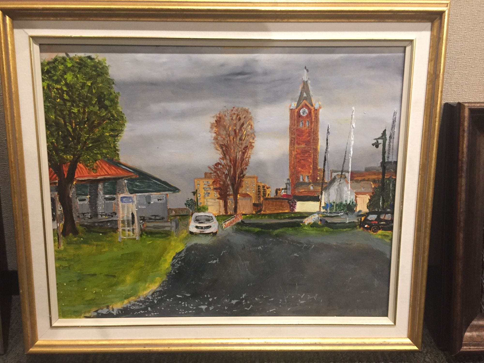 Framed painting looking down a street toward a red-brick clock tower.
