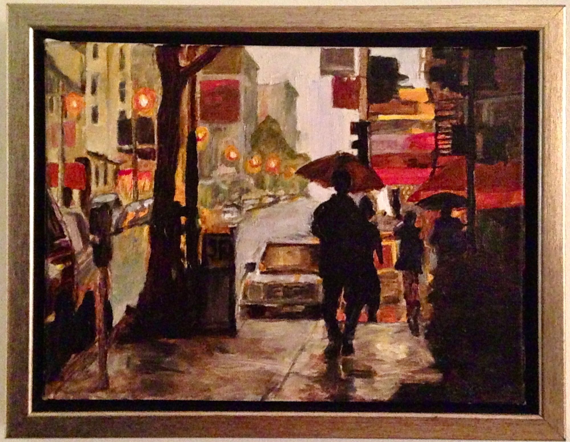 Framed painting of umbrella-carrying figures on a wet city street.